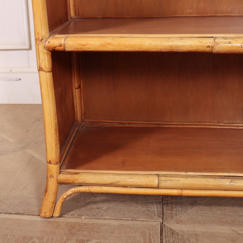 A pair of low vintage bamboo bookcases featuring woven cane tops and two open wooden shelves. View X
