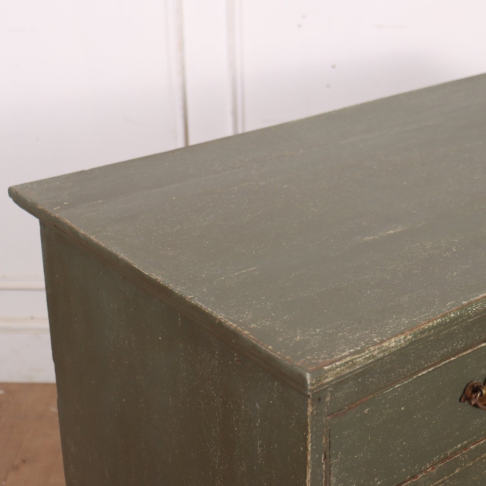 A distressed sage green painted wooden chest of drawers featuring two short over three long drawers with decorative brass handles and bracket feet. View VIII