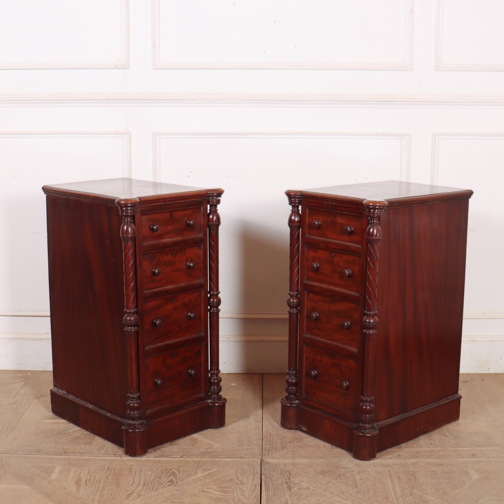 A matching pair of tall mahogany bedside chests featuring four drawers each, turned twist column pilasters, and round wooden handles. View V