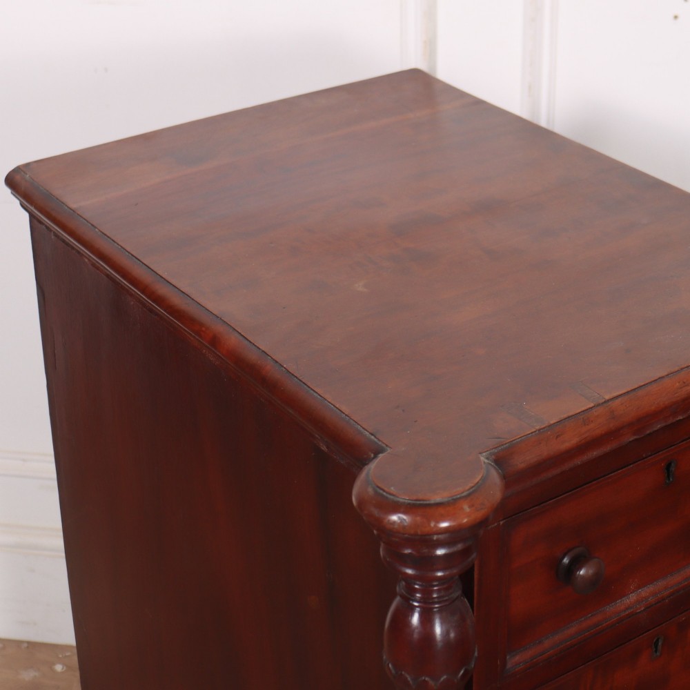 A matching pair of tall mahogany bedside chests featuring four drawers each, turned twist column pilasters, and round wooden handles. View VI