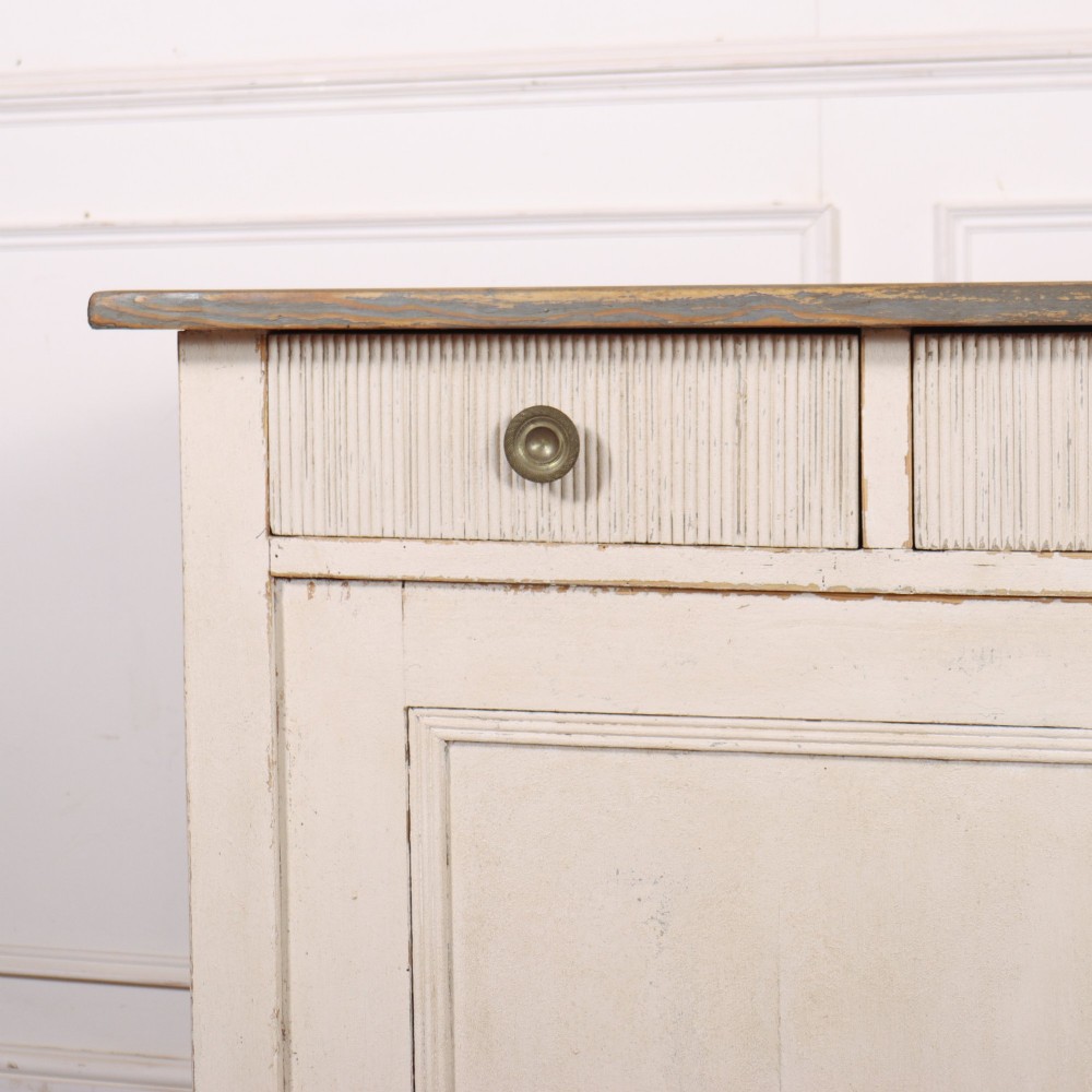 An off-white painted Continental wooden buffet featuring three reeded top drawers with round brass knobs above two large panelled cupboard doors and a grey painted top surface. View II