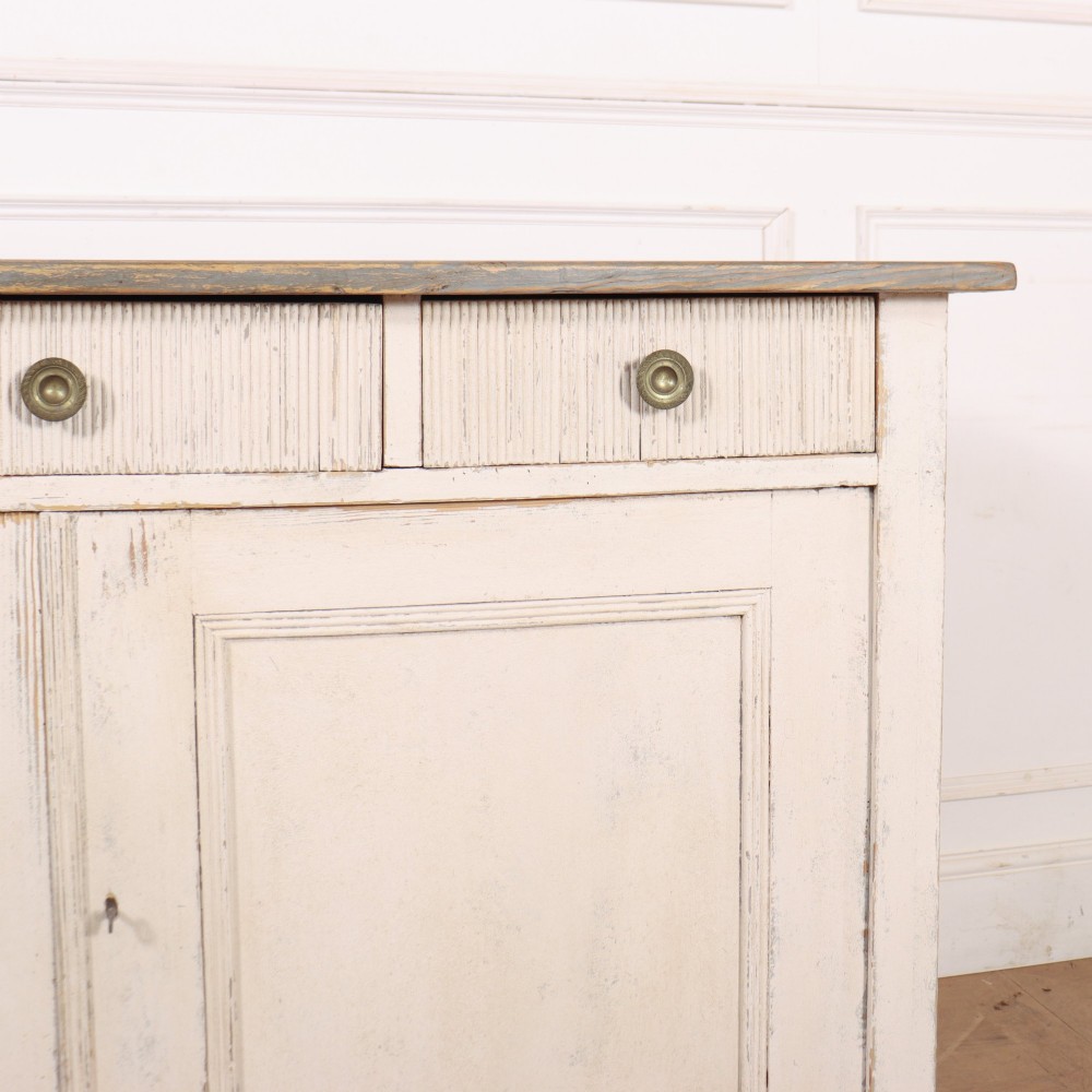 An off-white painted Continental wooden buffet featuring three reeded top drawers with round brass knobs above two large panelled cupboard doors and a grey painted top surface. View IV