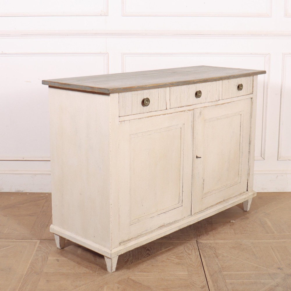 An off-white painted Continental wooden buffet featuring three reeded top drawers with round brass knobs above two large panelled cupboard doors and a grey painted top surface. View IX