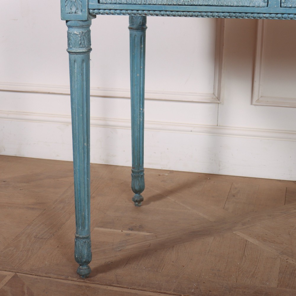 An Italian Neoclassical style light blue painted console table featuring a white marble top, three carved frieze drawers, and fluted legs. View V