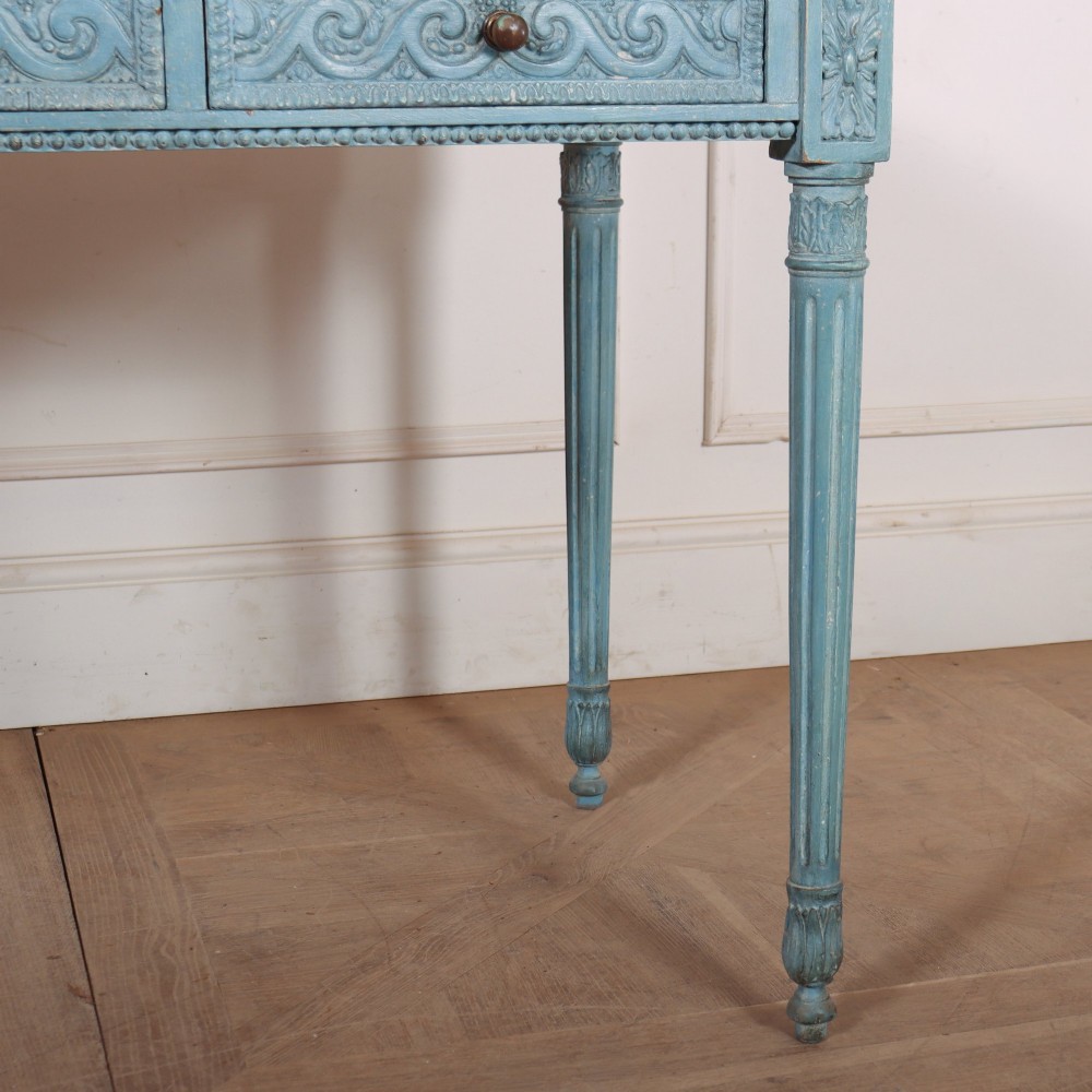 An Italian Neoclassical style light blue painted console table featuring a white marble top, three carved frieze drawers, and fluted legs. View VI