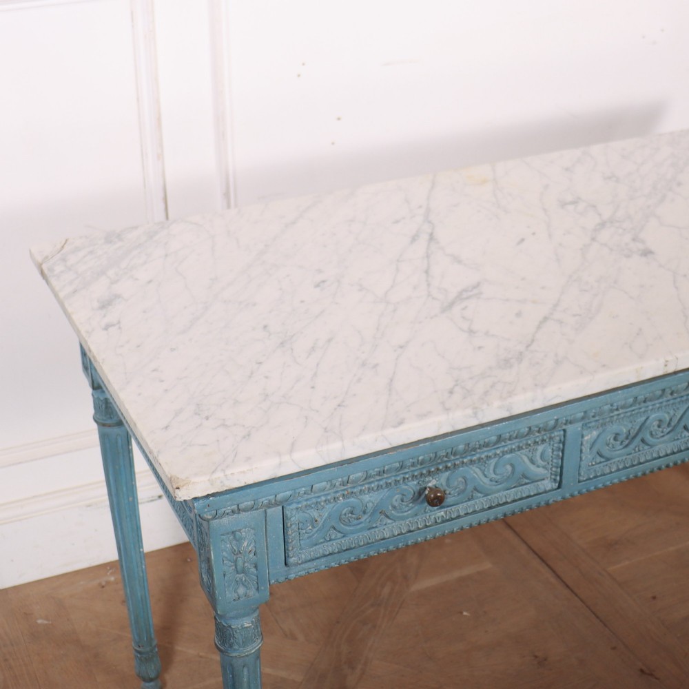 An Italian Neoclassical style light blue painted console table featuring a white marble top, three carved frieze drawers, and fluted legs. View VII