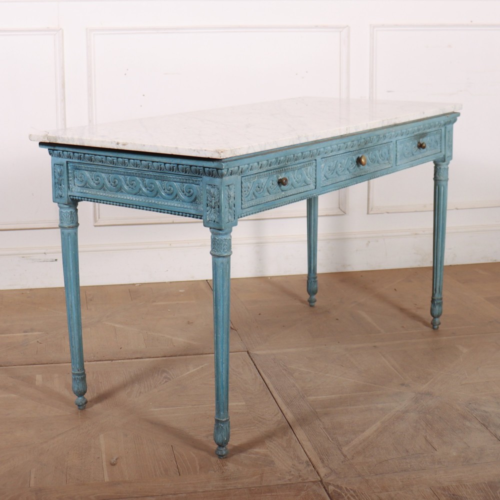 An Italian Neoclassical style light blue painted console table featuring a white marble top, three carved frieze drawers, and fluted legs. View X