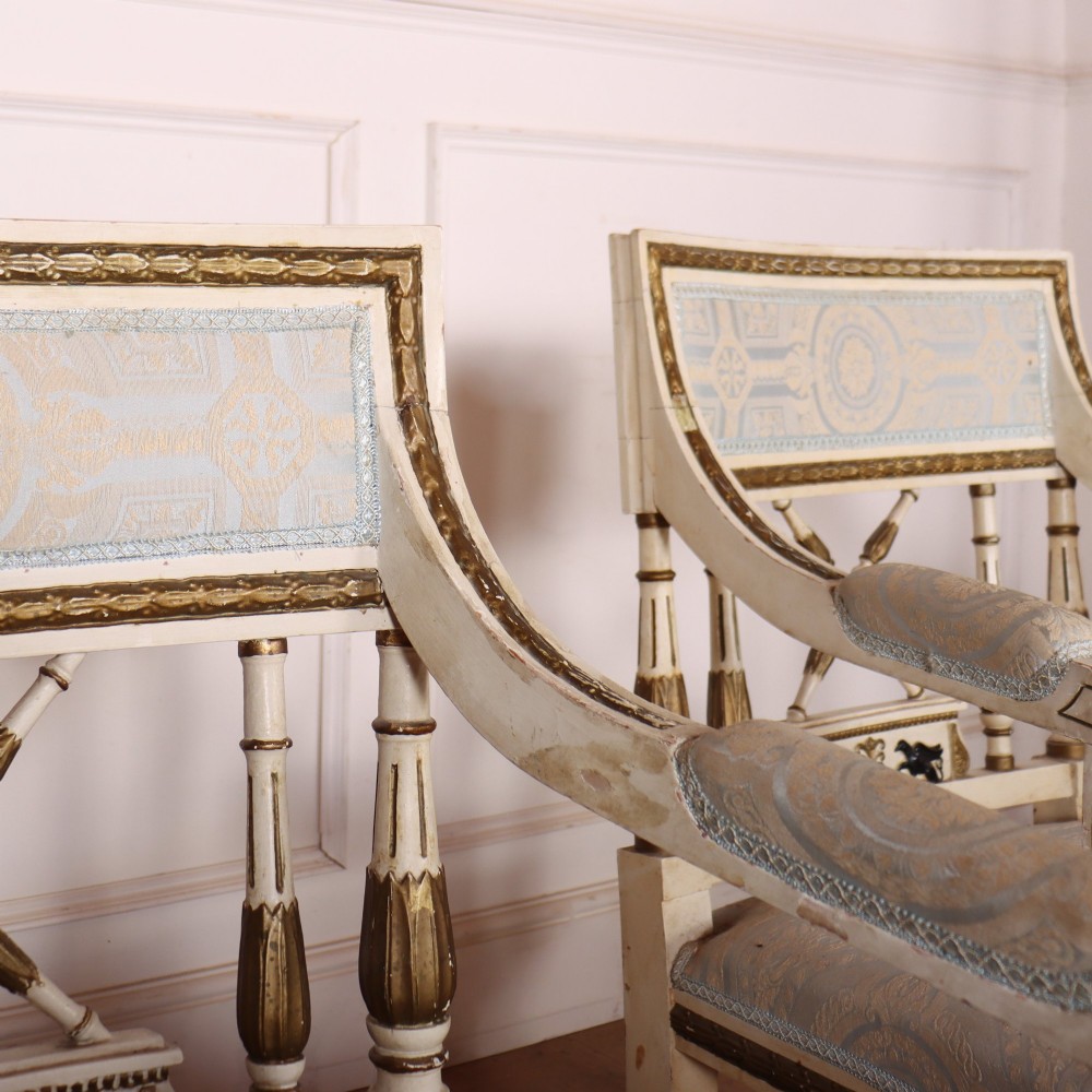 A pair of Swedish Empire style armchairs with pale cream and gilt painted frames, X-back spindle details, and light blue patterned fabric upholstery. View VII