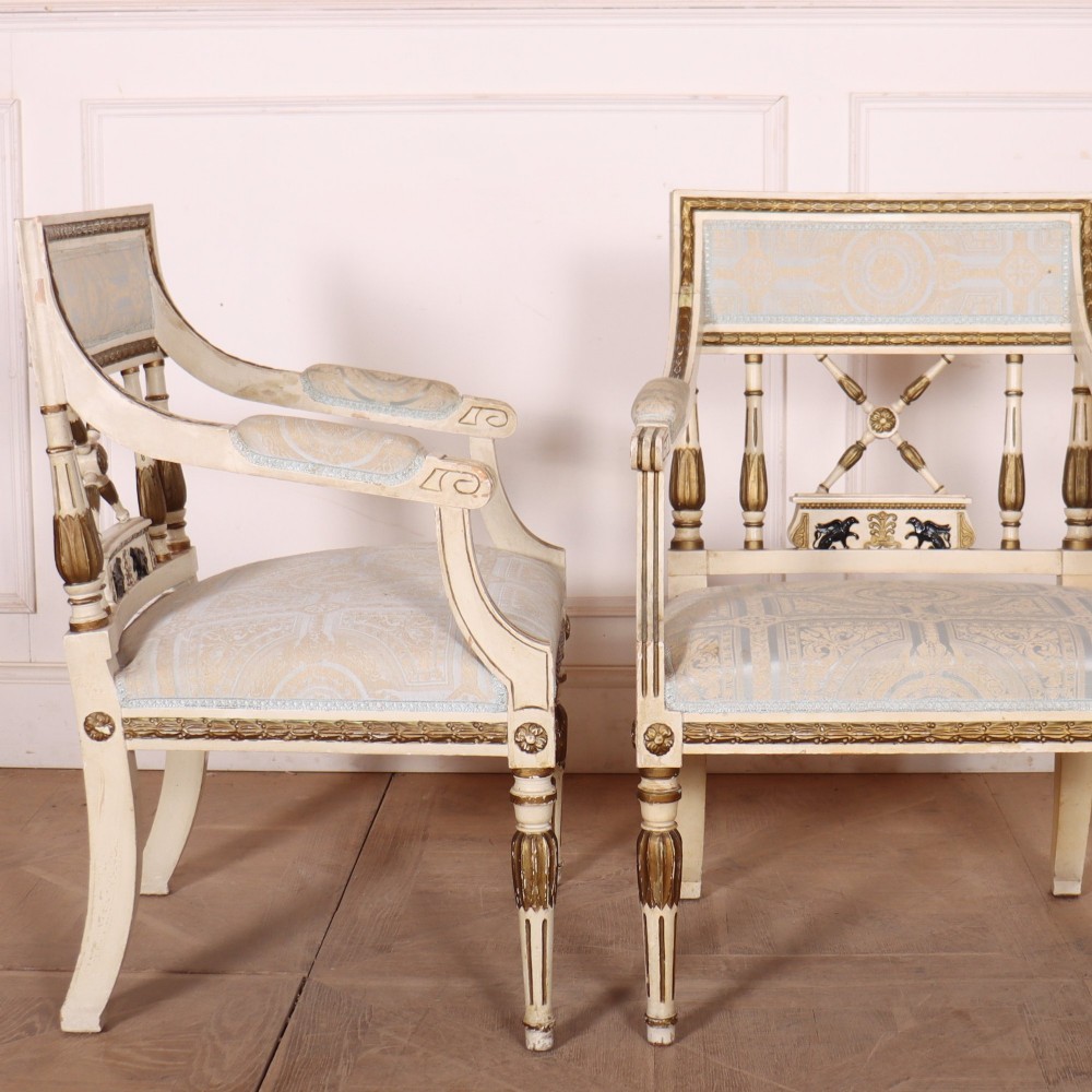 A pair of Swedish Empire style armchairs with pale cream and gilt painted frames, X-back spindle details, and light blue patterned fabric upholstery. View IX