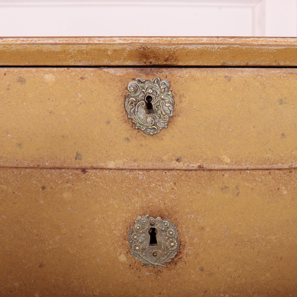 An antique French four-drawer wooden commode featuring an ochre painted finish with brass ring pull handles and central keyhole escutcheons. View VI