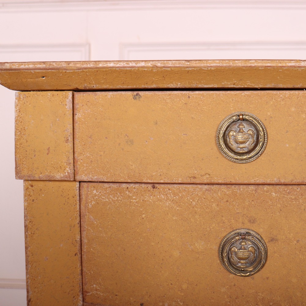 An antique French four-drawer wooden commode featuring an ochre painted finish with brass ring pull handles and central keyhole escutcheons. View VII