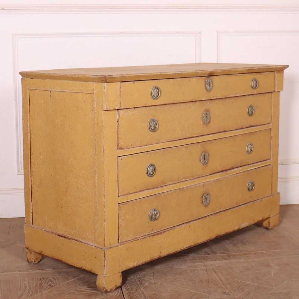 An antique French four-drawer wooden commode featuring an ochre painted finish with brass ring pull handles and central keyhole escutcheons. View VIII