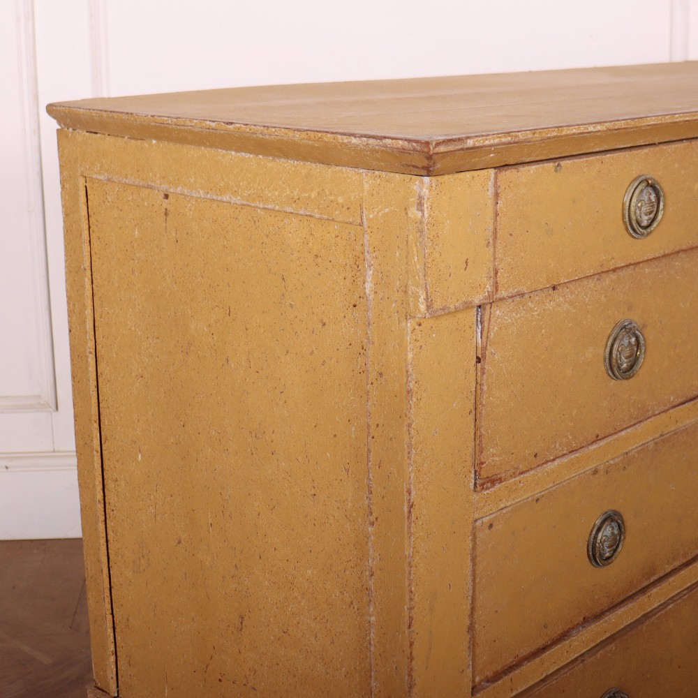 An antique French four-drawer wooden commode featuring an ochre painted finish with brass ring pull handles and central keyhole escutcheons. View IX