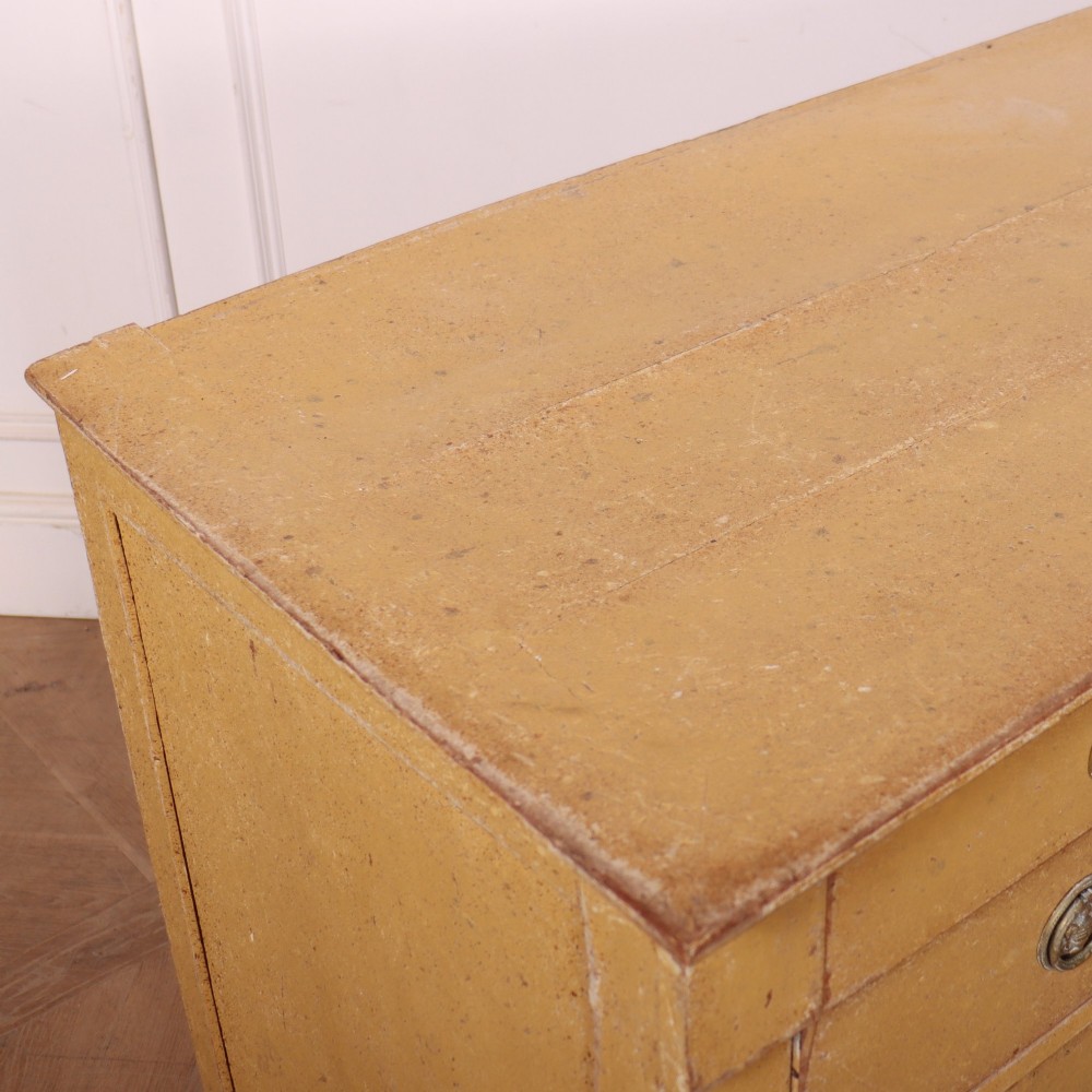 An antique French four-drawer wooden commode featuring an ochre painted finish with brass ring pull handles and central keyhole escutcheons. View XI