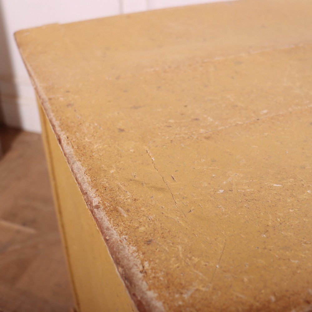 An antique French four-drawer wooden commode featuring an ochre painted finish with brass ring pull handles and central keyhole escutcheons. View XIV