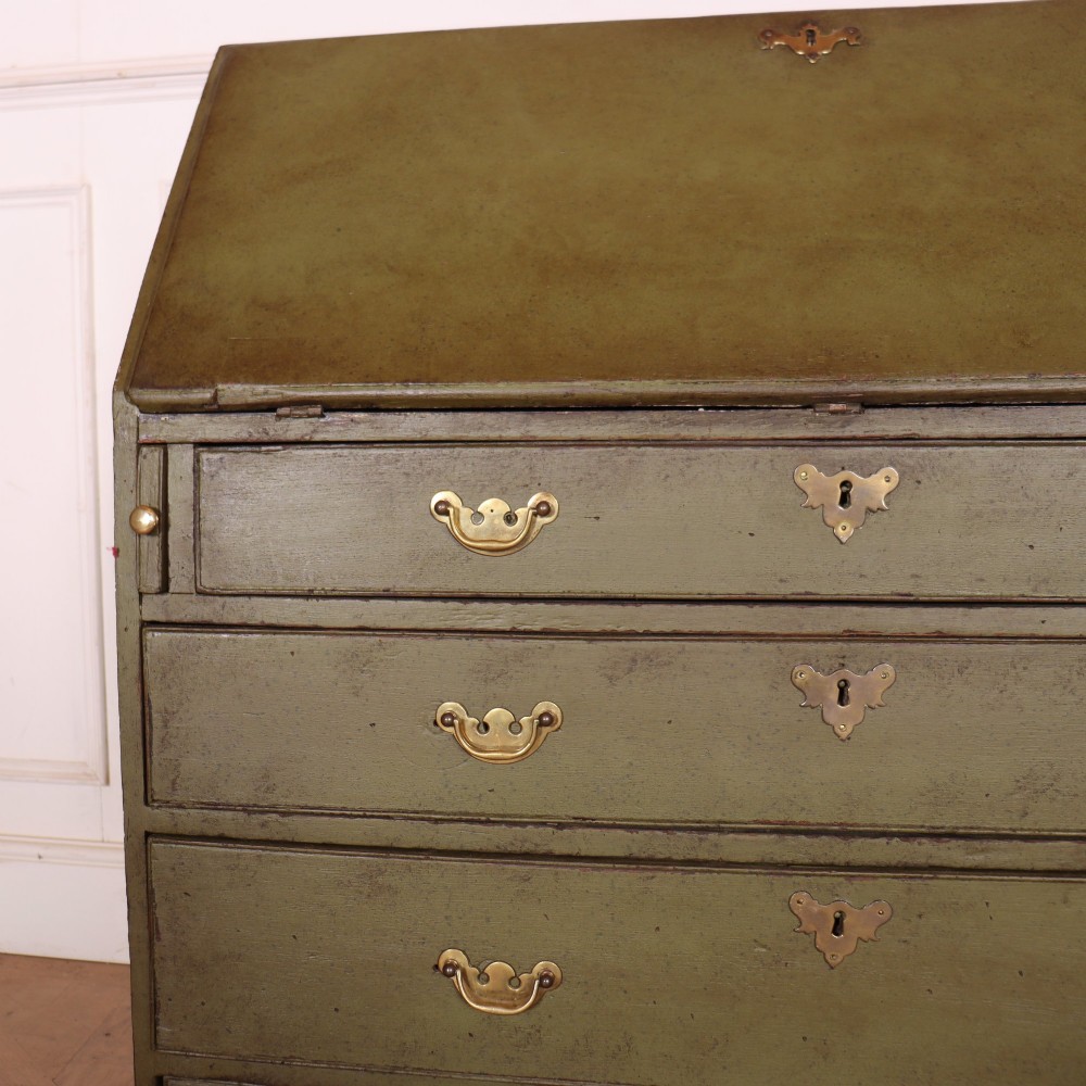 An antique English slant-front bureau with an olive green painted finish, brass handles, keyhole escutcheons, and four drawers resting on bracket feet. View II