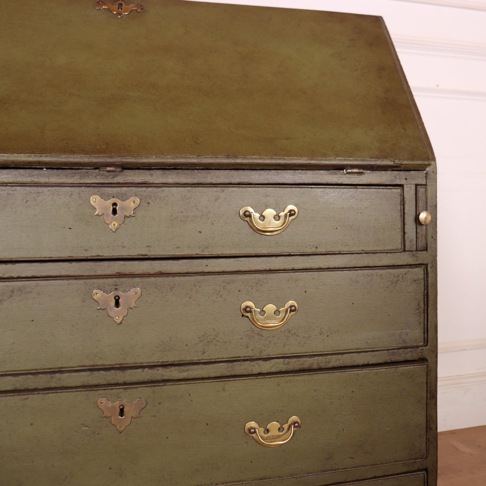 An antique English slant-front bureau with an olive green painted finish, brass handles, keyhole escutcheons, and four drawers resting on bracket feet. View III