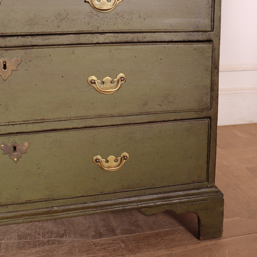 An antique English slant-front bureau with an olive green painted finish, brass handles, keyhole escutcheons, and four drawers resting on bracket feet. View IV