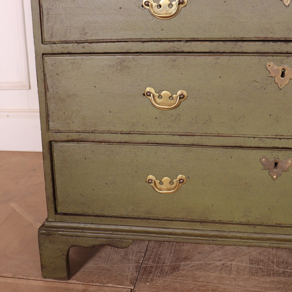 An antique English slant-front bureau with an olive green painted finish, brass handles, keyhole escutcheons, and four drawers resting on bracket feet. View V