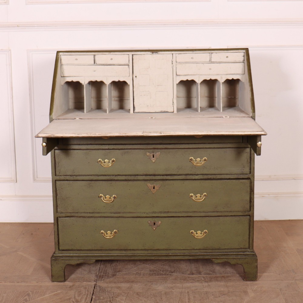 An antique English slant-front bureau with an olive green painted finish, brass handles, keyhole escutcheons, and four drawers resting on bracket feet. View VII