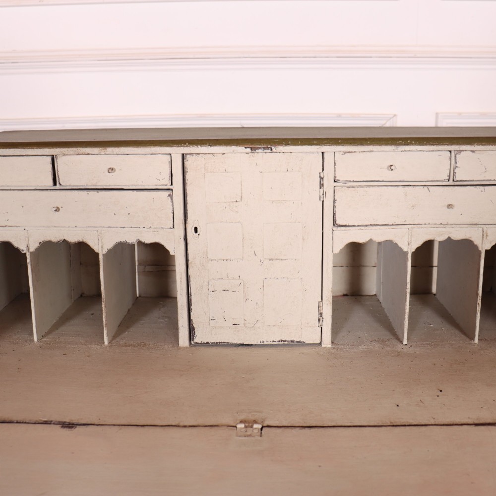 An antique English slant-front bureau with an olive green painted finish, brass handles, keyhole escutcheons, and four drawers resting on bracket feet. View IX