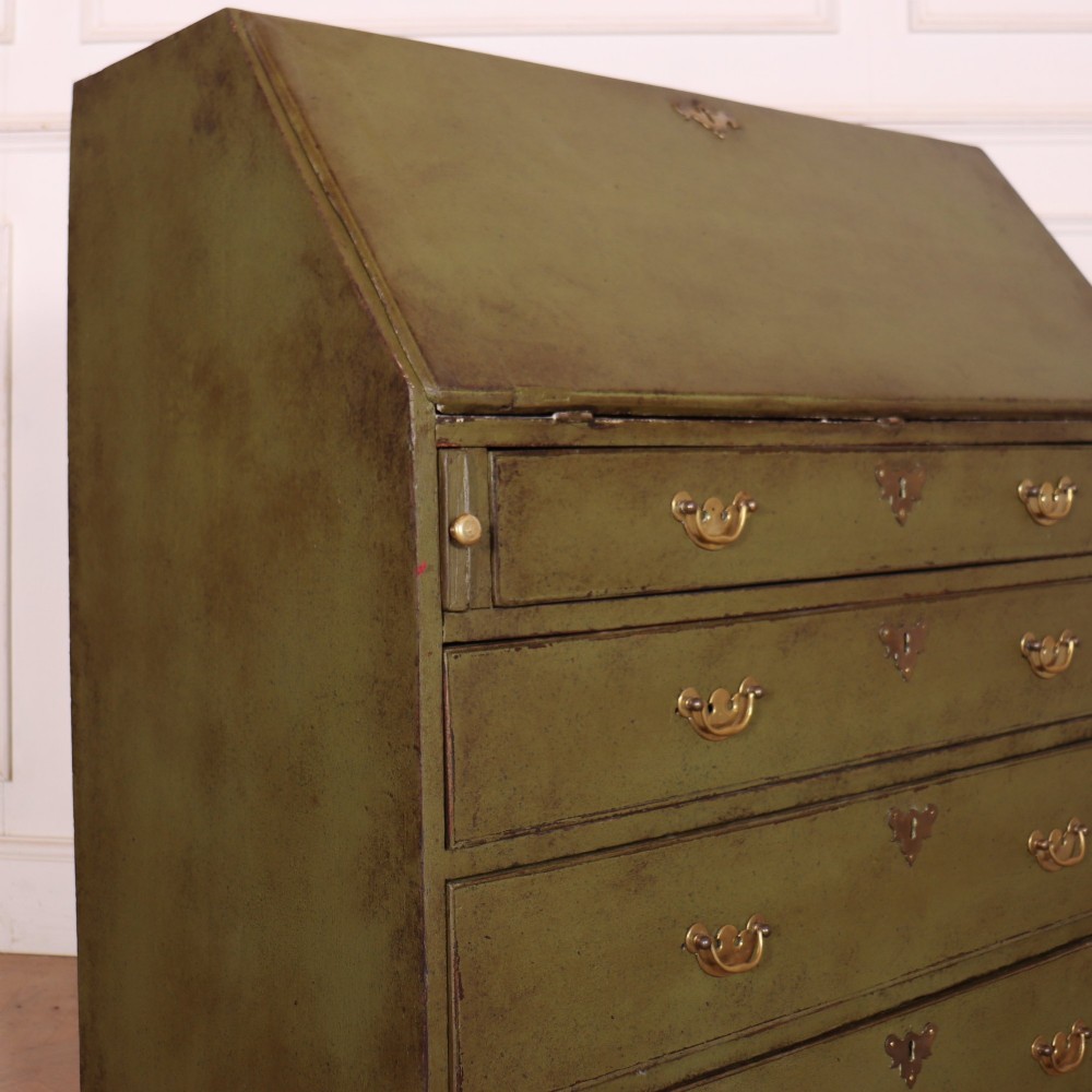 An antique English slant-front bureau with an olive green painted finish, brass handles, keyhole escutcheons, and four drawers resting on bracket feet. View XIV