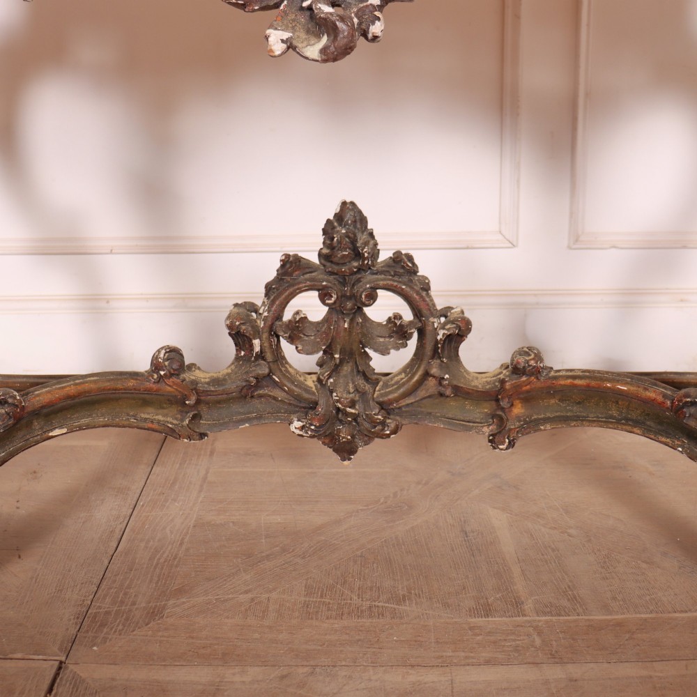 An antique French Rococo style console table featuring a cream marble top, elaborate rocaille carved giltwood apron, cabriole legs, and a decorative central stretcher. View V