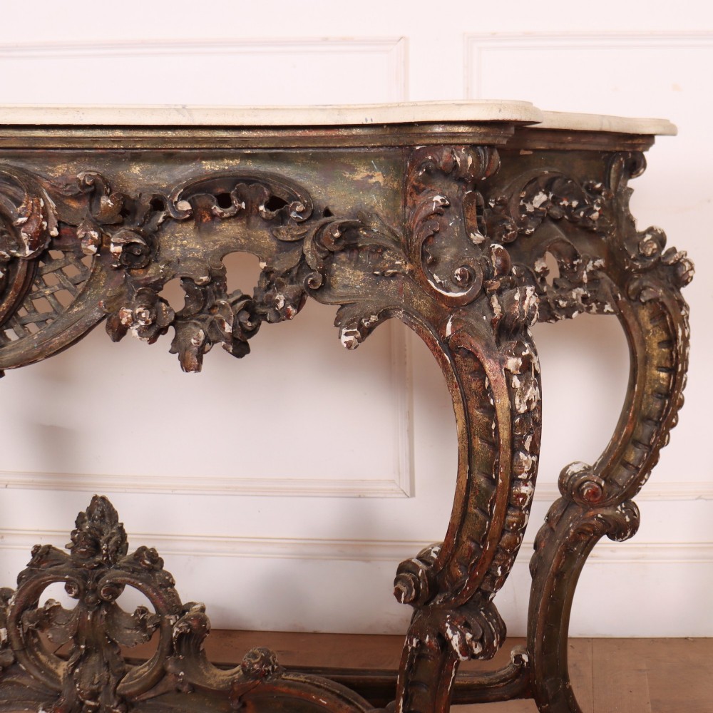 An antique French Rococo style console table featuring a cream marble top, elaborate rocaille carved giltwood apron, cabriole legs, and a decorative central stretcher. View VI
