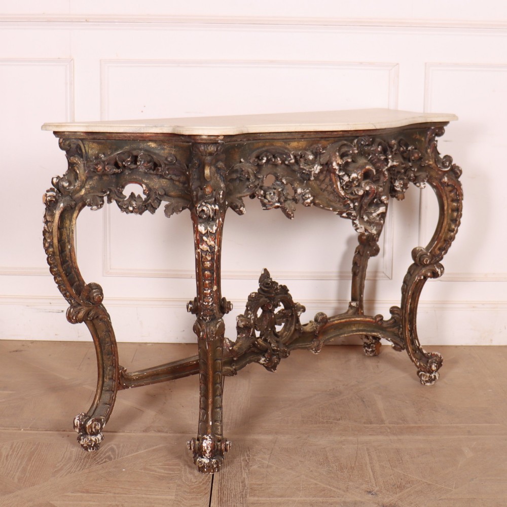 An antique French Rococo style console table featuring a cream marble top, elaborate rocaille carved giltwood apron, cabriole legs, and a decorative central stretcher. View VIII