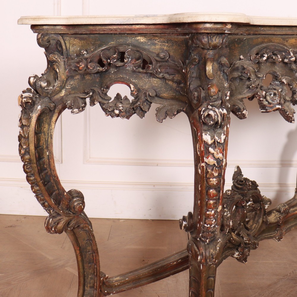 An antique French Rococo style console table featuring a cream marble top, elaborate rocaille carved giltwood apron, cabriole legs, and a decorative central stretcher. View IX