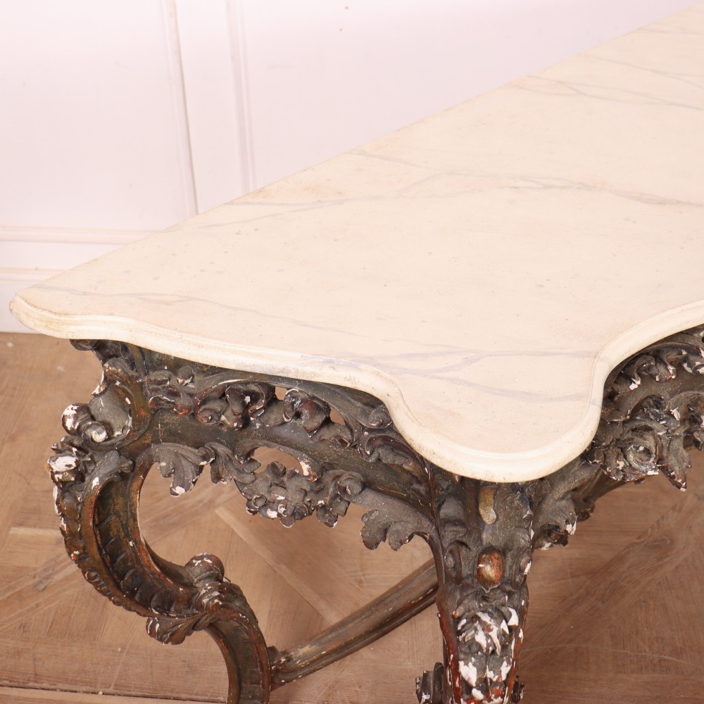 An antique French Rococo style console table featuring a cream marble top, elaborate rocaille carved giltwood apron, cabriole legs, and a decorative central stretcher. View XI