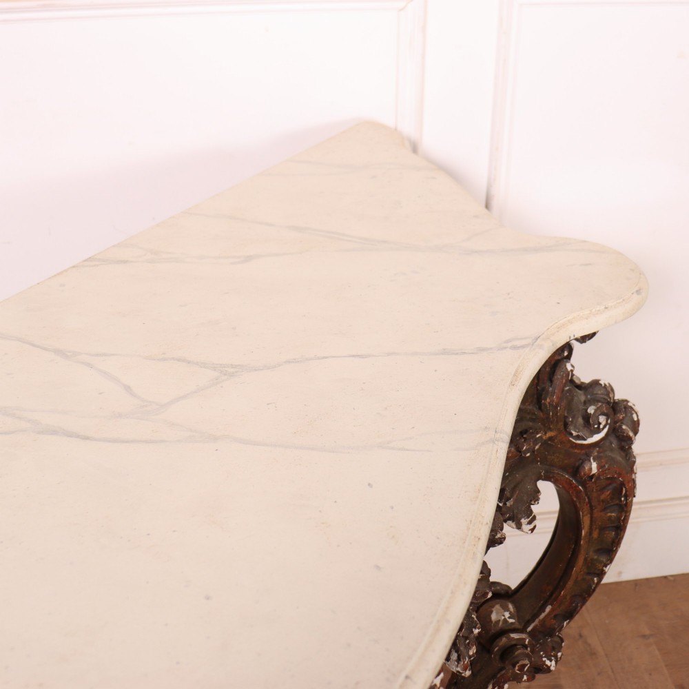 An antique French Rococo style console table featuring a cream marble top, elaborate rocaille carved giltwood apron, cabriole legs, and a decorative central stretcher. View XII