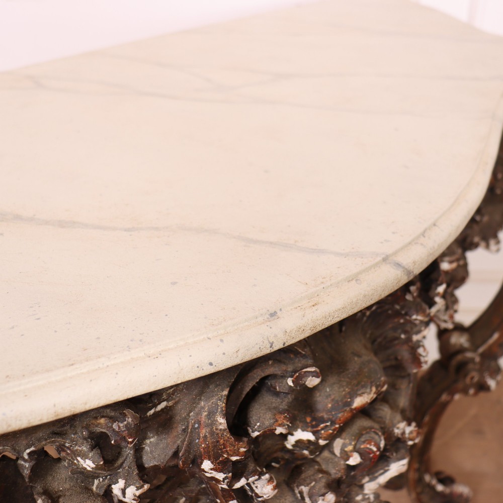 An antique French Rococo style console table featuring a cream marble top, elaborate rocaille carved giltwood apron, cabriole legs, and a decorative central stretcher. View XIII