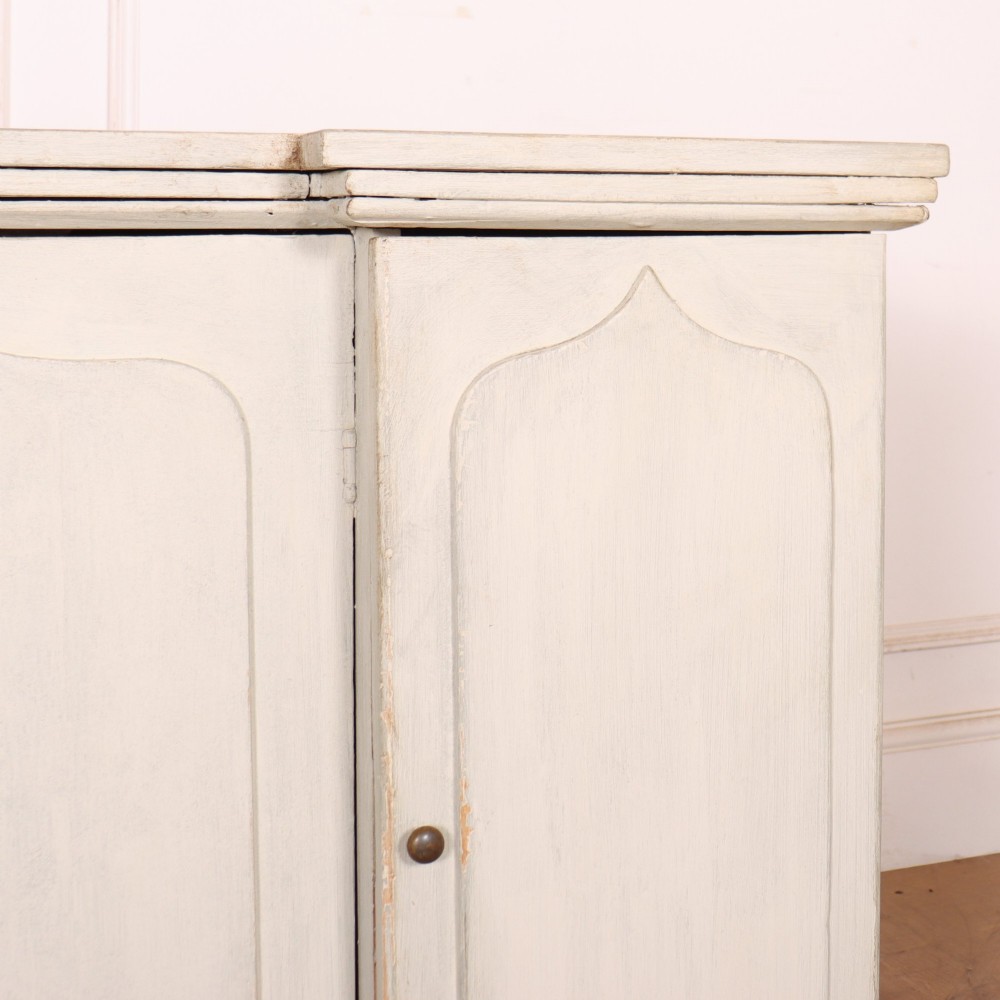 An off-white painted breakfront dresser base featuring four cupboard doors with arched panel mouldings and small brass knobs. View VI