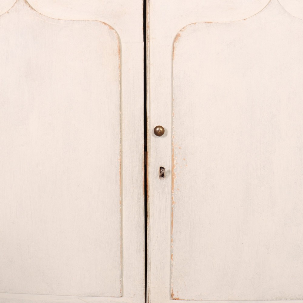 An off-white painted breakfront dresser base featuring four cupboard doors with arched panel mouldings and small brass knobs. View VIII