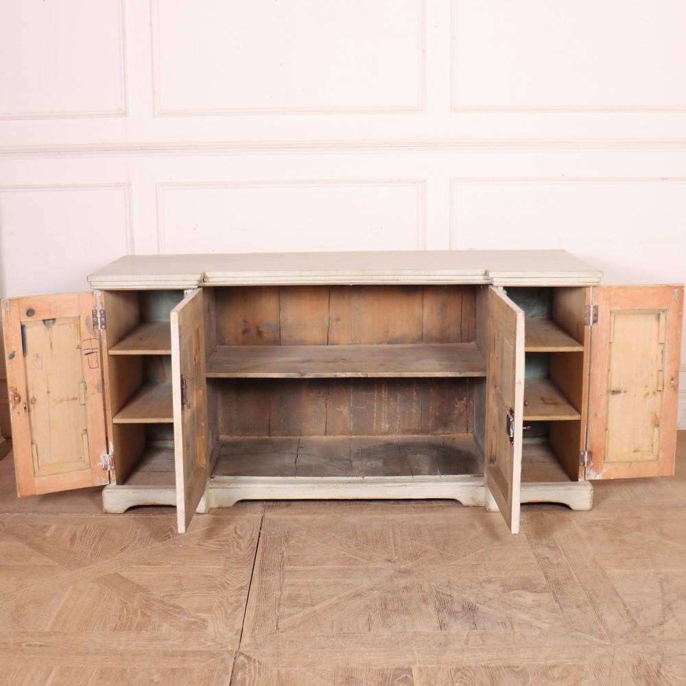An off-white painted breakfront dresser base featuring four cupboard doors with arched panel mouldings and small brass knobs. View IX