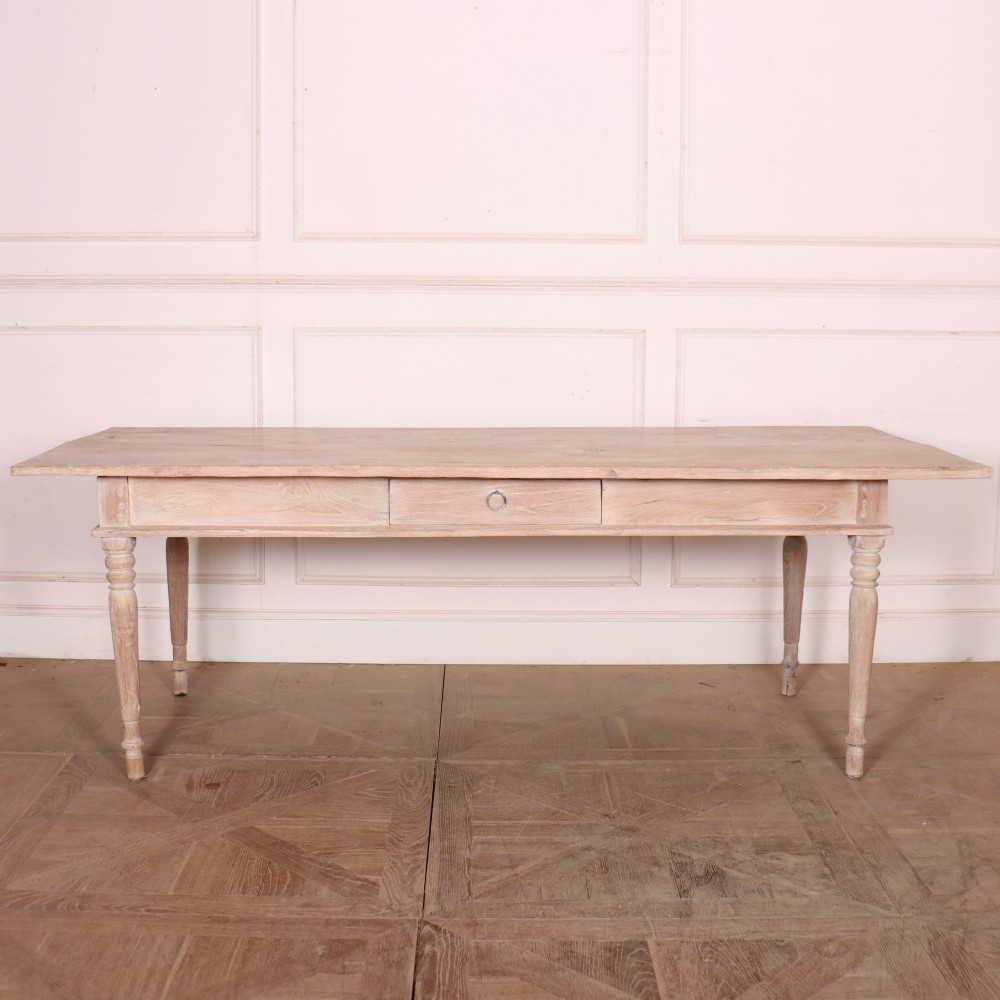A 19th-century Spanish rustic elm dining table featuring a pale natural finish, four turned legs, and a single frieze drawer with a metal ring pull.