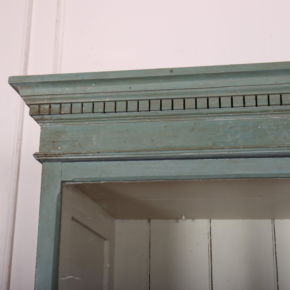 A tall two-part painted muted blue wood cabinet featuring an upper section with two glazed glass doors over a lower cupboard base with two drawers and panelled doors. View II