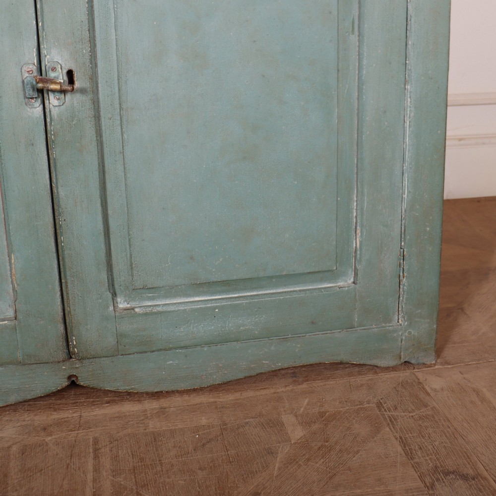 A tall two-part painted muted blue wood cabinet featuring an upper section with two glazed glass doors over a lower cupboard base with two drawers and panelled doors. View VII