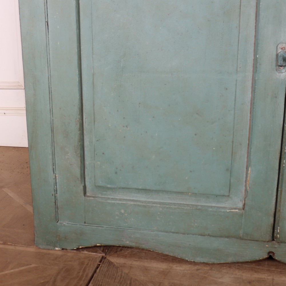 A tall two-part painted muted blue wood cabinet featuring an upper section with two glazed glass doors over a lower cupboard base with two drawers and panelled doors. View VIII