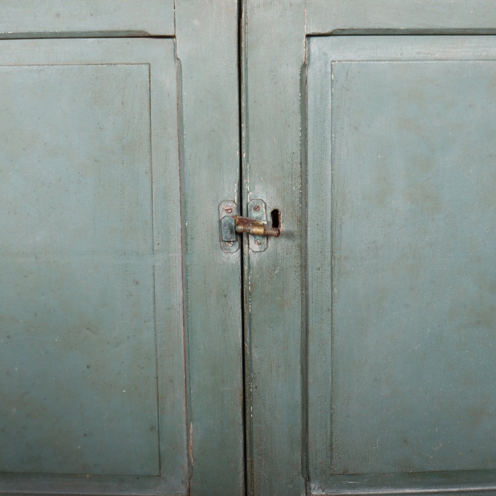 A tall two-part painted muted blue wood cabinet featuring an upper section with two glazed glass doors over a lower cupboard base with two drawers and panelled doors. View IX