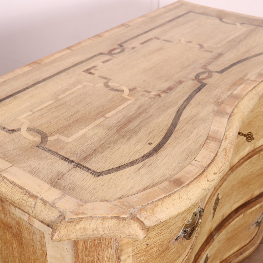 An Austrian bleached oak commode featuring a serpentine front, three drawers with crossbanded borders, brass escutcheons, handles, and turned feet. View XI