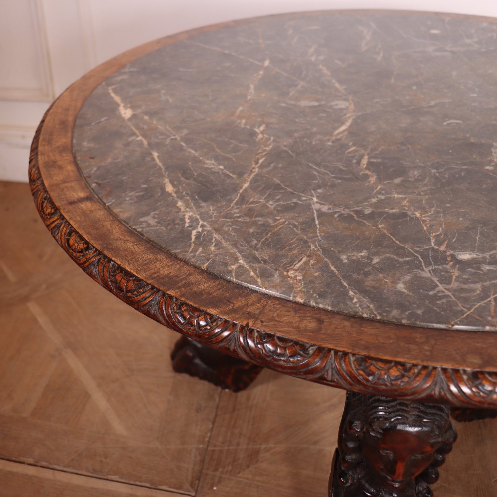 A circular dark wood lamp table featuring an inset dark marble top, intricately carved floral borders, and carved caryatid legs resting on paw feet. View II