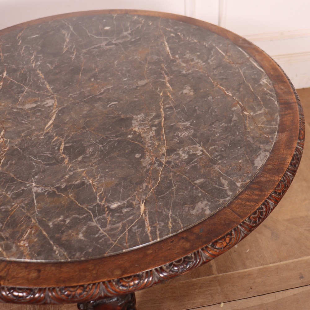 A circular dark wood lamp table featuring an inset dark marble top, intricately carved floral borders, and carved caryatid legs resting on paw feet. View III