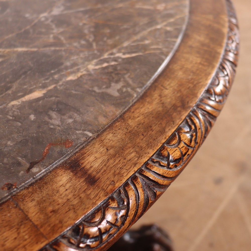 A circular dark wood lamp table featuring an inset dark marble top, intricately carved floral borders, and carved caryatid legs resting on paw feet. View V