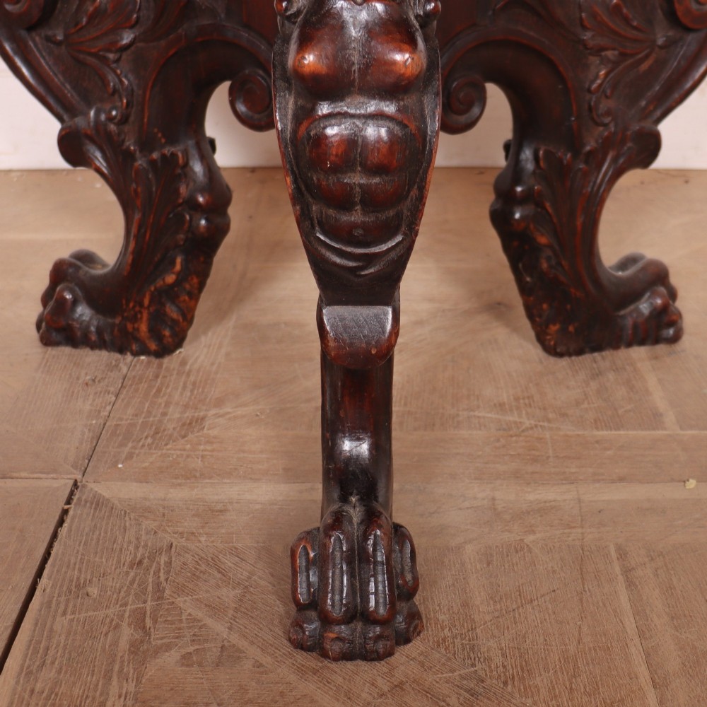 A circular dark wood lamp table featuring an inset dark marble top, intricately carved floral borders, and carved caryatid legs resting on paw feet. View VIII