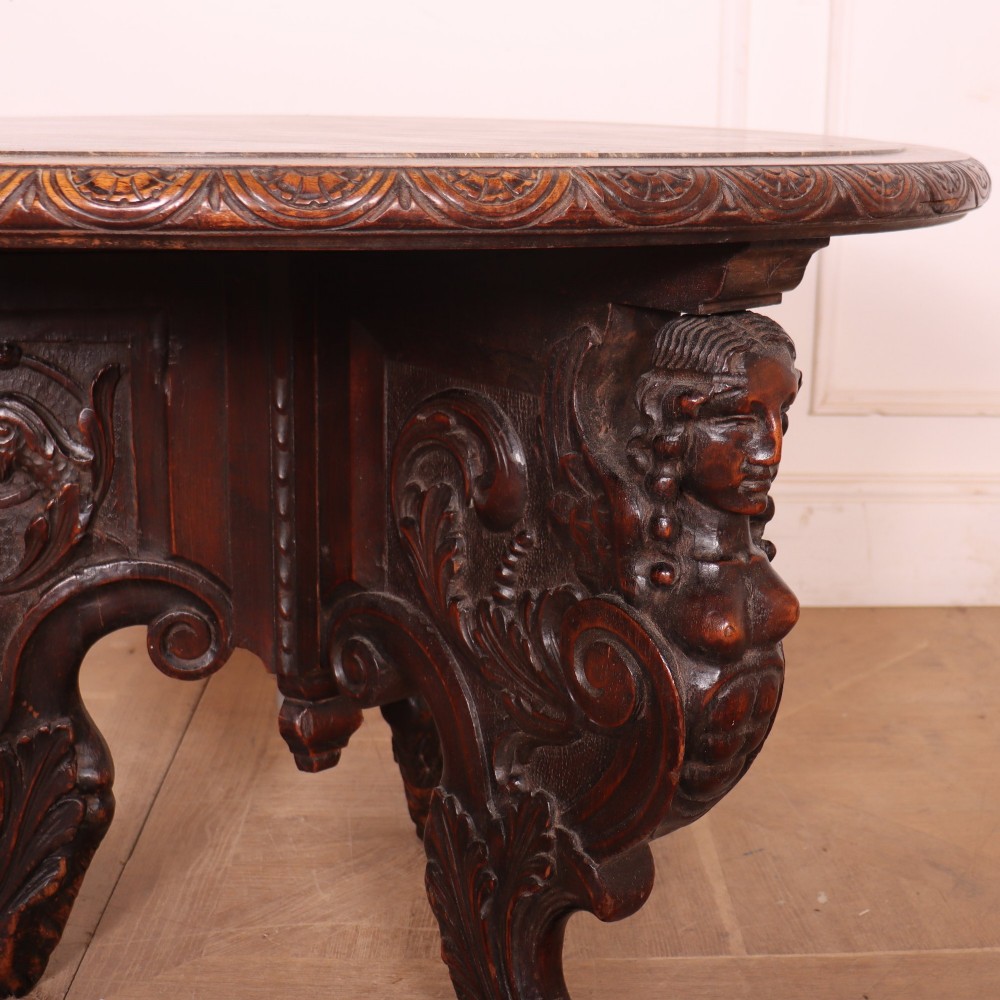 A circular dark wood lamp table featuring an inset dark marble top, intricately carved floral borders, and carved caryatid legs resting on paw feet. View IX