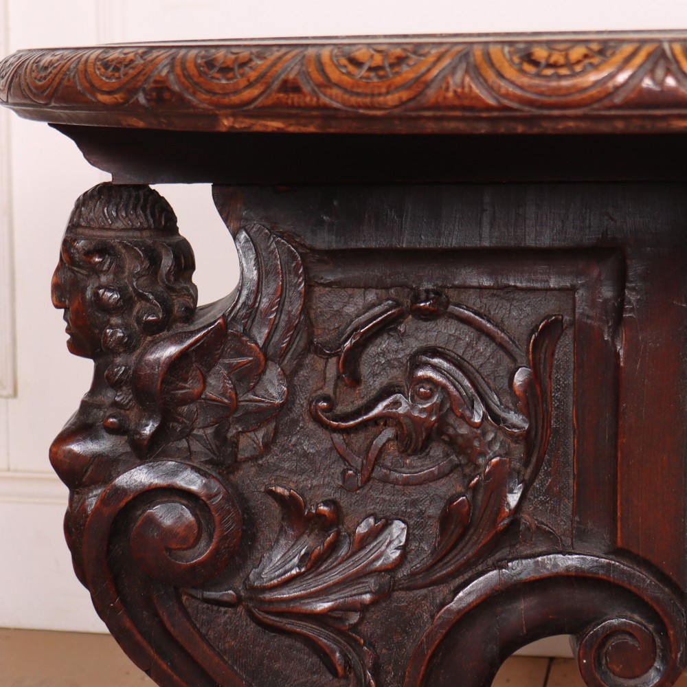 A circular dark wood lamp table featuring an inset dark marble top, intricately carved floral borders, and carved caryatid legs resting on paw feet. View XI
