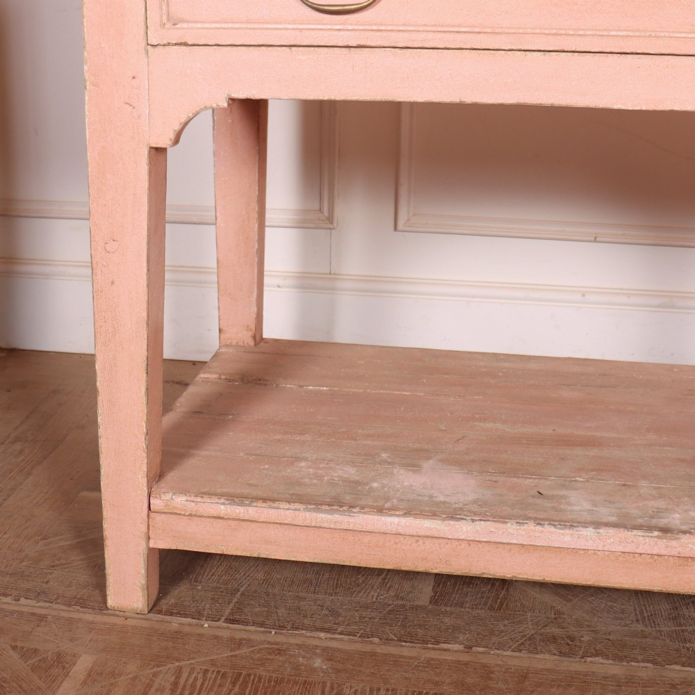 A Scottish farmhouse potboard dresser base with a painted pink frame, wide drawers fitted with brass handles, and an open lower wooden shelf. View III