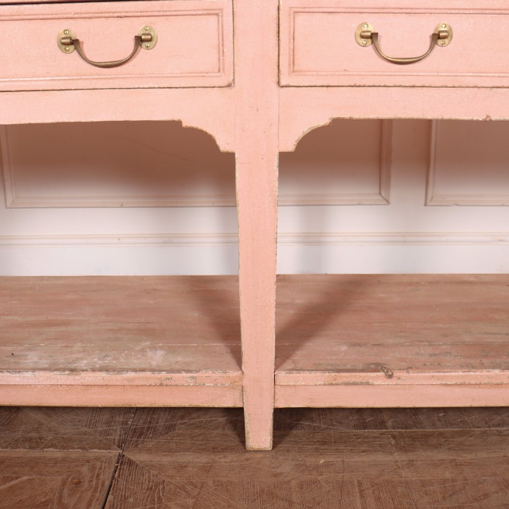 A Scottish farmhouse potboard dresser base with a painted pink frame, wide drawers fitted with brass handles, and an open lower wooden shelf. View V